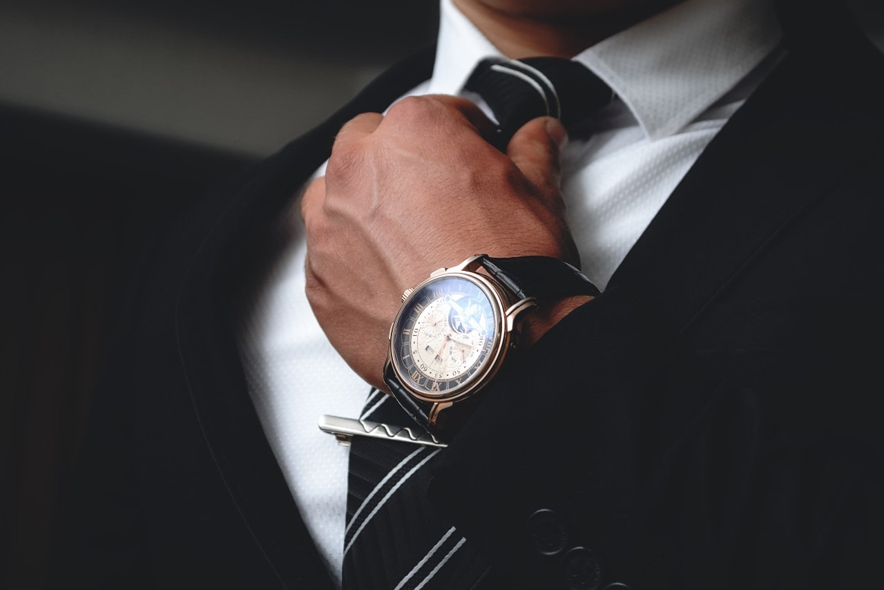 Man touching his tie and wearing a vintage watch on his wrist