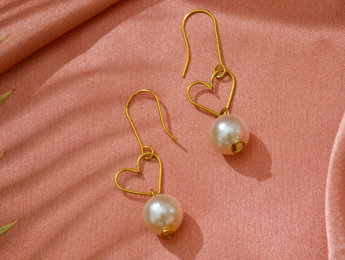 A pair of heart-shaped earrings with pearls