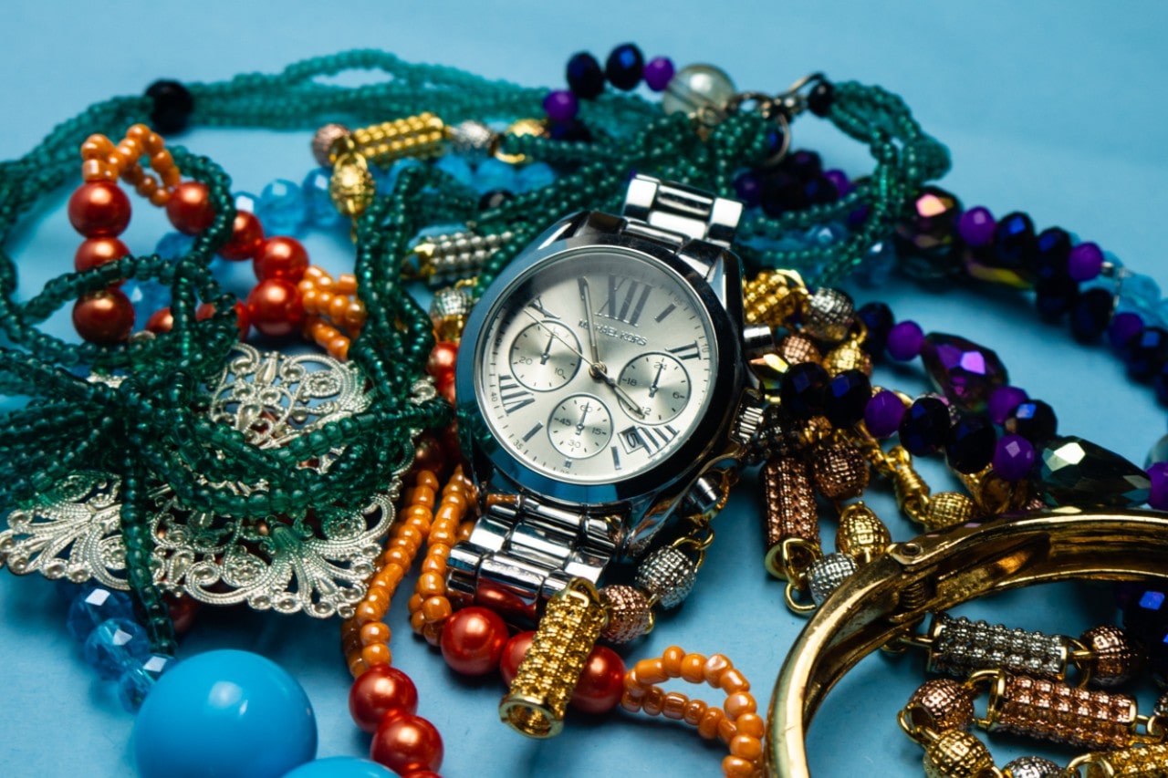 A silver vintage-inspired watch sitting on a bed of colorful beaded jewelry