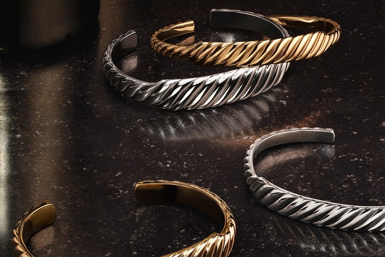 David Yurman cuff bracelets in silver and gold on a black marble slab