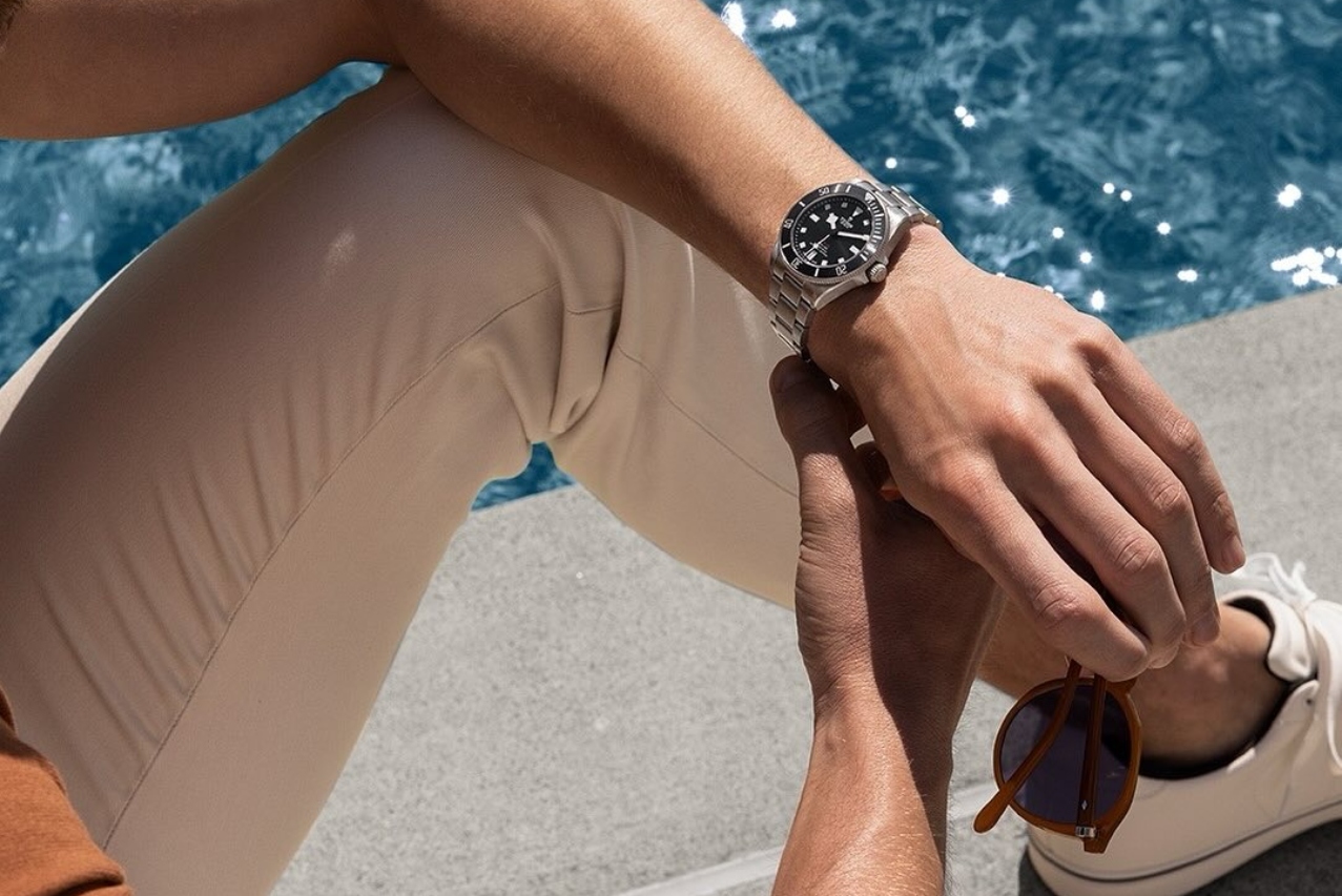 A close-up of a person checking their watch at the poolside.