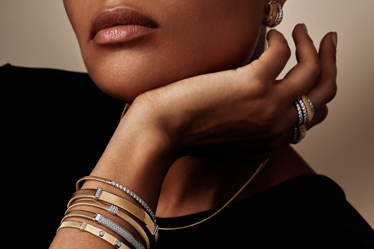 A close-up of a fashionable woman adorned in matching yellow gold and diamond jewelry.