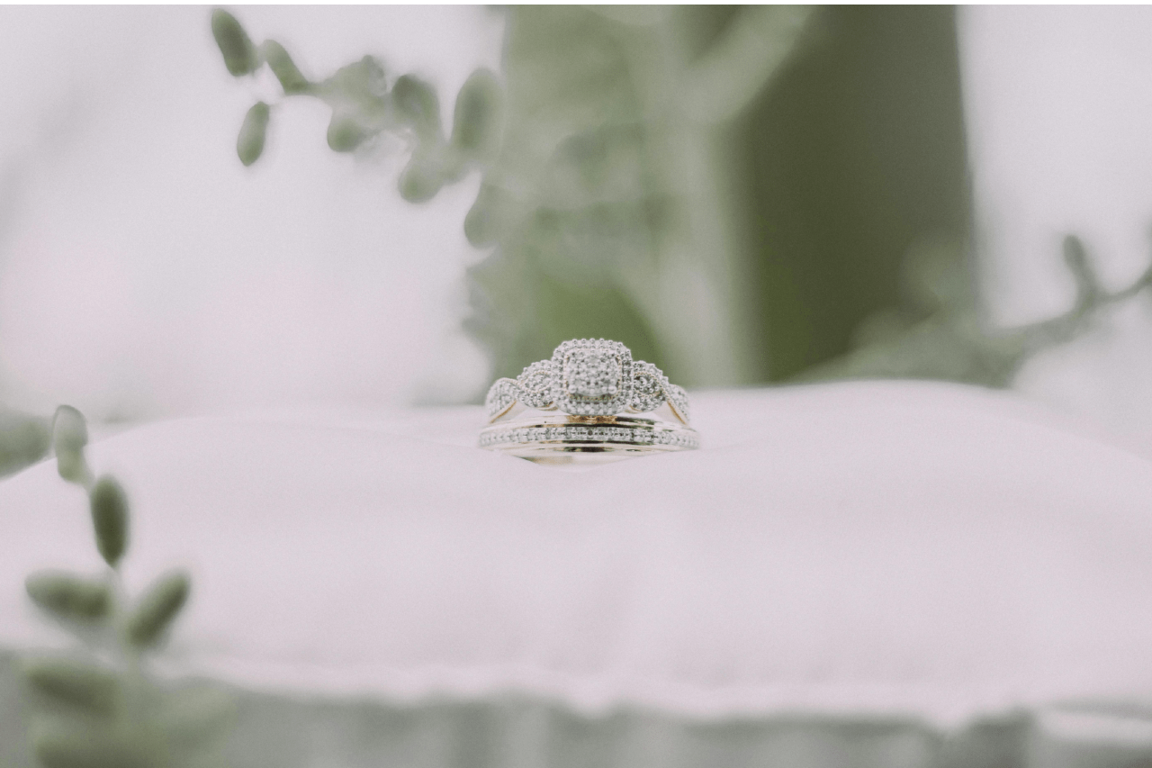 a white gold engagement ring and wedding band set on a white pillow