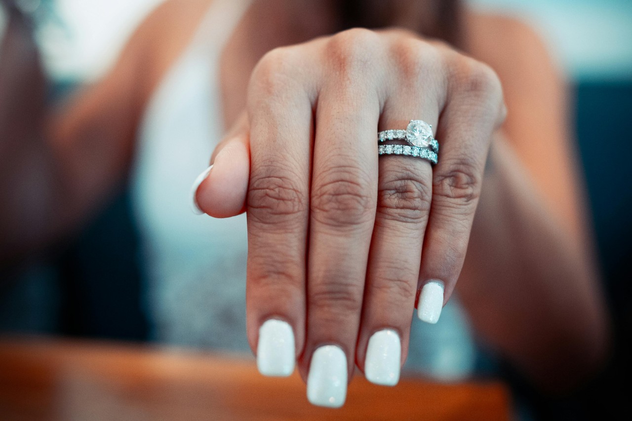 a woman’s extended hand showing off a matching engagement ring and wedding band set