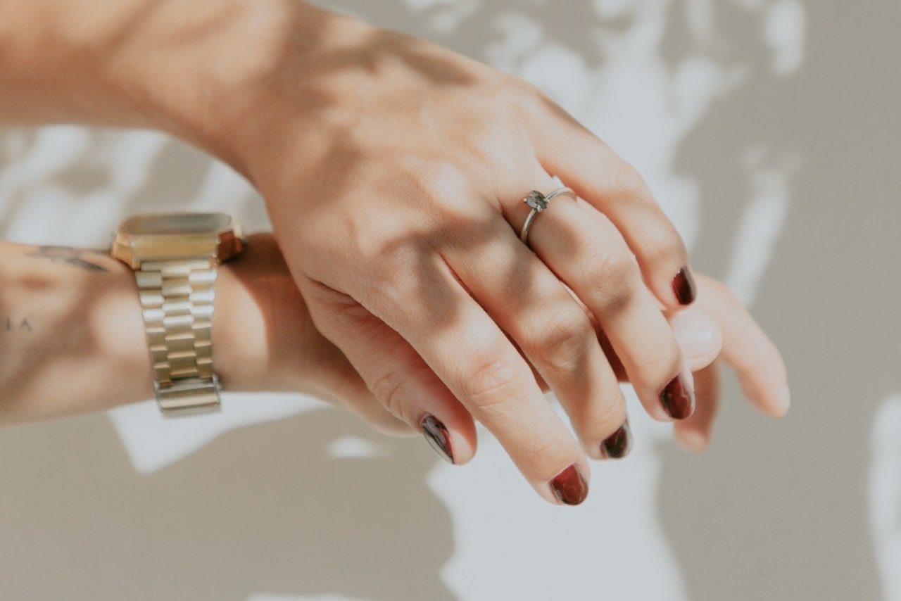 A woman wearing a gold TAG Heuer watch and a solitaire engagement ring.