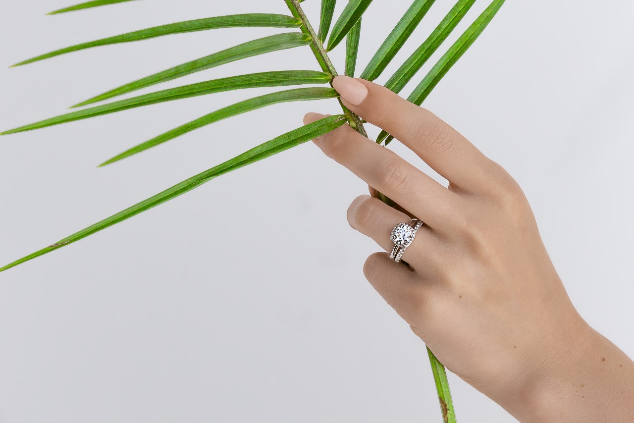 A Tacori engagement ring on the hand of a woman holding a palm frond.